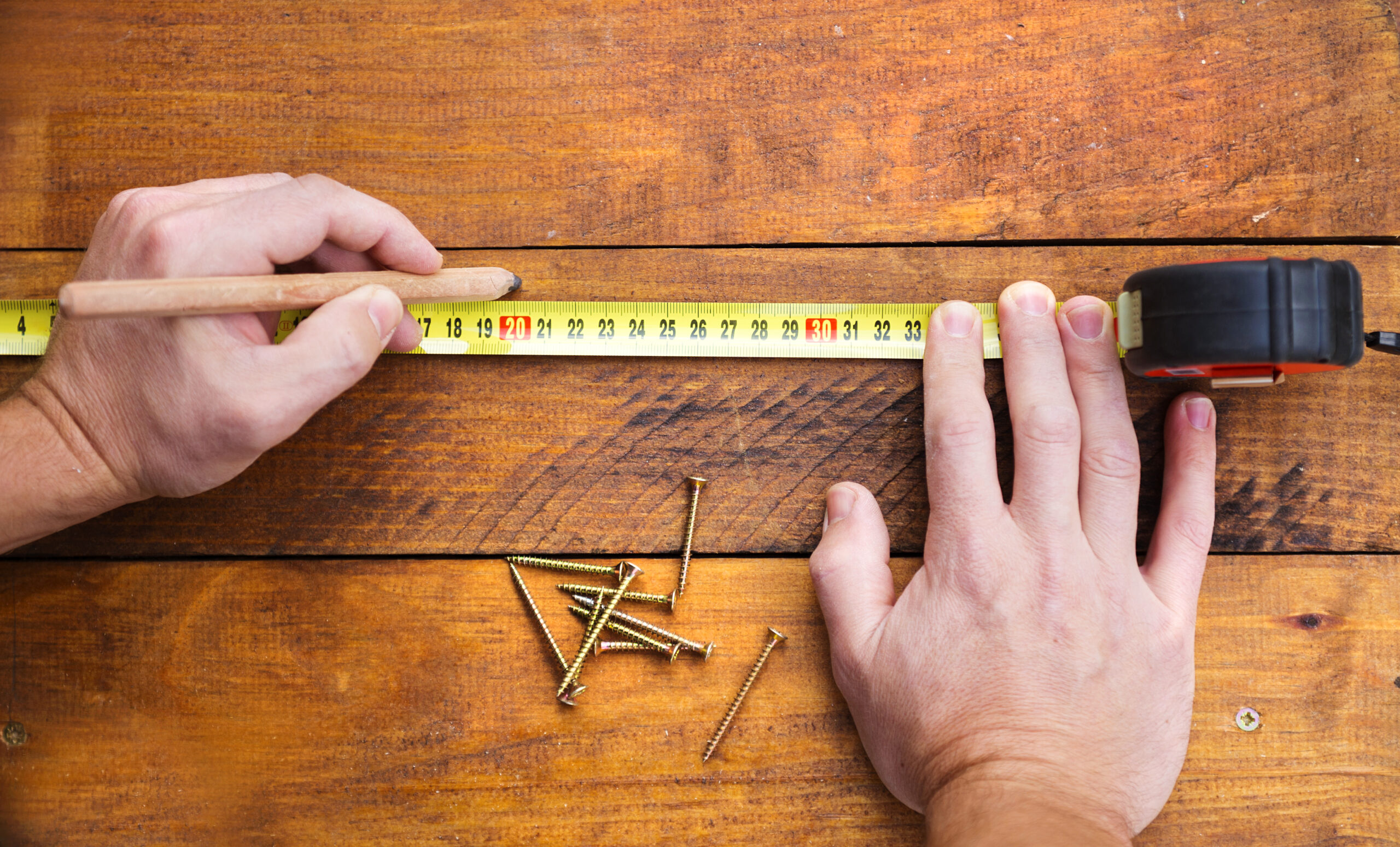 graphicstock-close-up-of-male-hand-measuring-and-marking-wood-flooring-with-tape-measure_rCPra2hWZ-scaled.jpg